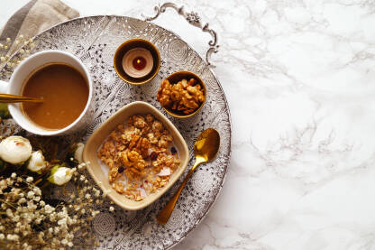 Granola sa orasima i bijelom kafom servirana uz aromatičnu svijeću za doručak