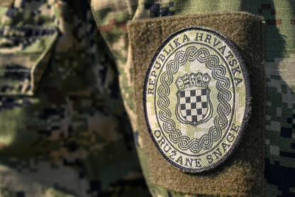 Hrvatska vojska. Oružane snage Republike Hrvatske tokom službene ceremonije. Hrvatska zastava na maskirnoj uniformi. Grb na ramenu vojnika.
