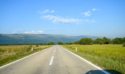 Duga ravna cesta u polju. Vožnja automobila u prirodi. Pogled vozača na asfaltnu cestu. Livanjsko polje.