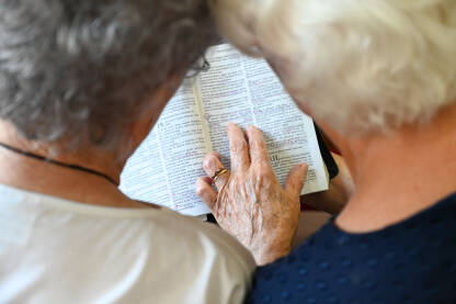 Starije žene mole se u crkvi. Gospođe drže knjigu tokom molitve. Vjernici se mole.