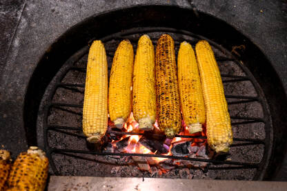 Kukuruz se peče na roštilju. Grilovani kukuruz u klipu na vrućoj vatri. Kukuruz za prodaju u gradu.