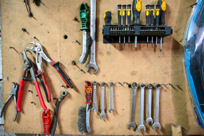 Alati visi na zidu u mehaničarskoj radionici. Set alata. Grupa ključeva, kliješta, odvijača, četki i čekića u garaži.