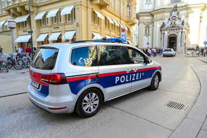 Policijsko vozilo patrolira ulicama u gradu Beču. Policijska patrola. Simbol: Policija.
