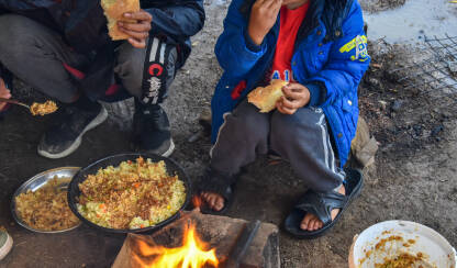 Dječak sjedi pored vatre i jede u improvizovanom kampu za izbjeglice i migrante u Velikoj Kladuši, Bosna i Hercegovina.