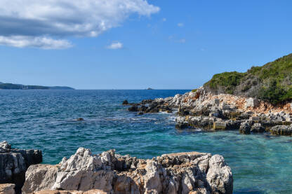 More tokom lijepog, sunčanog dana. Plava morska pučina, stijene i ostrvo u vodi.