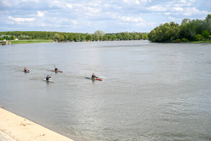 Mladi veslaju na kajaku na rijeci. Ljudi u čamcima po vodi.
