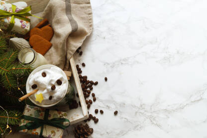 Kafa sa šlagom na stolu sa dekoracijom za zimske praznike.