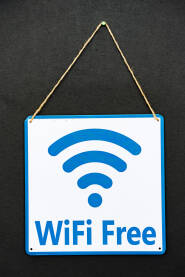 Plavo-beli natpis koji visi na crnoj pozadini i piše "wifi besplatno" bijelim slovima. Natpis je pričvršćen za uže.