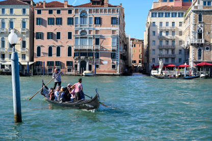 Venecija, Italija: Historijske građevine duž riječnog kanala. Popularno turističko odredište. Gondola sa turistima na vodi.
