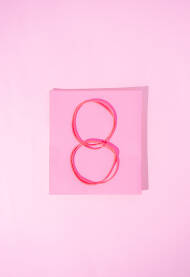 Broj osam, 8, napravljen od gumenih gumica za kosu na papirnoj podloti u obliku kvadrata pink, roze boje. Međunarodni Dan žena, 8. mart, koncept.