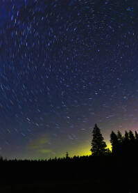Duga ekspozicija zvjezdanog neba sa Sjevejrnjačom i tragovima zvijezda, linijama, koje rotiraju oko nje sa siluetama crnogorične šume na Nišićkoj visoravni, Bijambare.