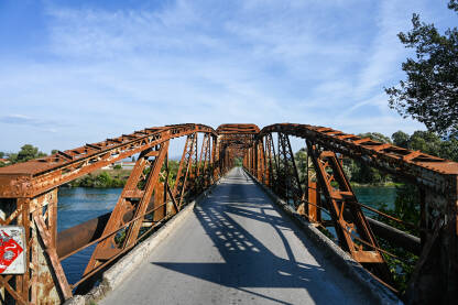 Stari zahrđali most preko rijeke. Stari metalni željeznički most. Čelični most preko rijeke.