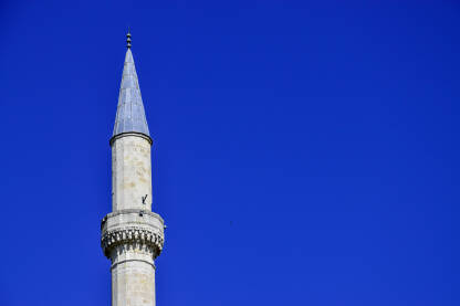 Vrh bijele munare tokom sučanog dana. Čisto plavo nebo i munara džamije.