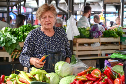 Starija žena prodaje voće i povrće na pijaci. Svježe organsko povrće na tržnici.