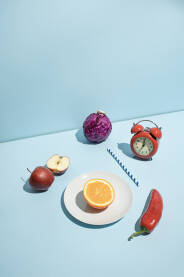 Svježe voće i povrće, retro sat i papirna slamka na plavoj pozadini.