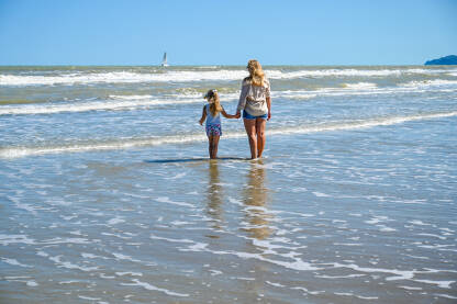 Majka sa kćerkom na pješčanoj plaži. Majka sa djetetom na moru. Turisti na godišnjem odmoru.