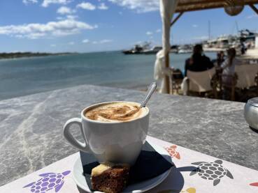 Šoljica kafe s kolačem i pogledom na more