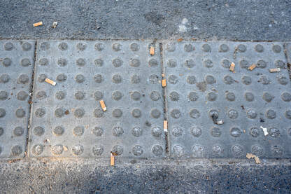 Filteri za cigarete bačeni na ulicu. Opušci bačeni na trotoar. Zagađenje u gradu.