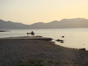 Osoba koja sjedi sama na morskoj obali.