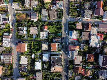 Snimak dronom na krovove kuća i zgrada u gradu. Pogled odozgo na stambene kuće i ulice sa parkiranim automobilima u gradu.