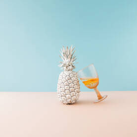 Svježi ananas obojen u bijelu boju i časa s pićem.