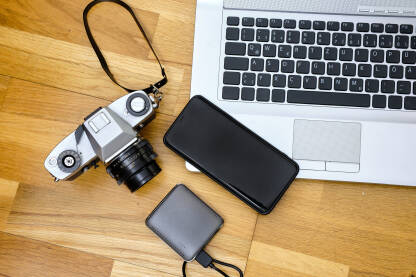 Laptop, telefon i fotoaparat na pozadini drvenog stola - koncept putovanje