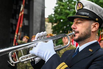 Muzičar s trubom. Vojnik u bijelim rukavicama svira trubu. Vojni orkestar na paradi.