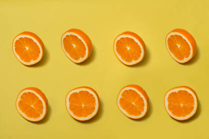 Narandže pogled odozgo, polovine zrelih narandži na žutoj pozadini
