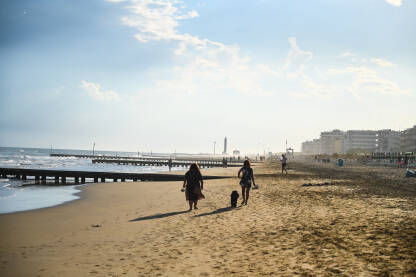 Plaža Jadranskog mora u Lido di Jesolo, Italija. Ljudi šetaju pješčanom plažom.