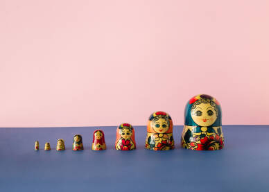 Ruske lutke babuške ili matrioške poredane na plavoj i roze pozadini.