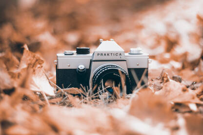 Analogni fotoaparat Praktica L. Stari analogni fotoaparat u jesen na opalom lišću.