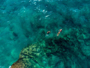 Kupači na moru tokom ljeta. Turisti rone i kupaju se u vodi. Prozirna morska voda u uvali.