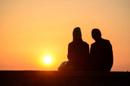 Silueta zaljubljenog para na moru tokom prekrasnog  zalaska sunca. Mladi i romantični par. Momak i djevojka na ljetovanju.