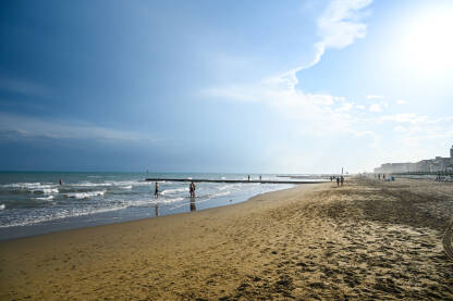 Plaža Jadranskog mora u Lido di Jesolo, Italija. Ljudi šetaju pješčanom plažom.