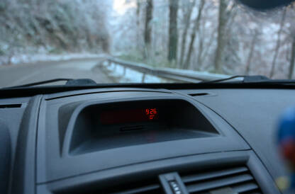 Vožnja automobila u planini zimi. Hladno jutro. Temperatura od 0 stepeni celzijusa prikazana u vozilu.