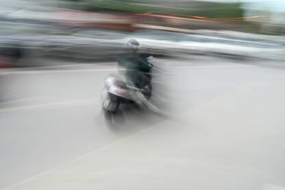 Motociklista na motoru brzo vozi kroz grad, blurana fotografija. Vožnja motocikla.