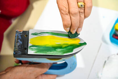 Enkaustično slikanje voskom i peglom. Umjetnost. Umjetnica dodaje boje na peglu.