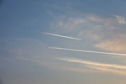 Linije na plavom nebu od prolaska aviona, delici oblaka u pozadini