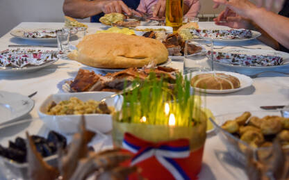 Porodica doručkuje na pravoslavni Božić. Božićna trpeza sa pečenicom, česnicom i drugom tradicionalnom hranom.