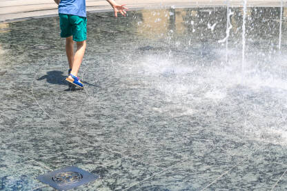 Dječak se osvježava na fontani ljeti.