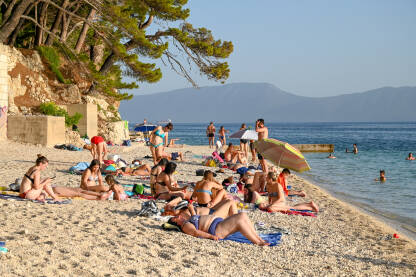 Turisti se kupaju na moru i sunčaju na plaži na Jadranskom moru. Turizam u Hrvatskoj ljeti.