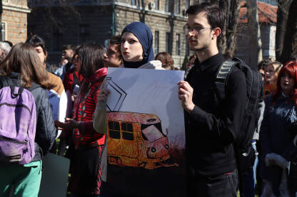 Dvoje mladih studenata na protestima u Sarajevu drže veliki poster s ilustracijom tramvaja