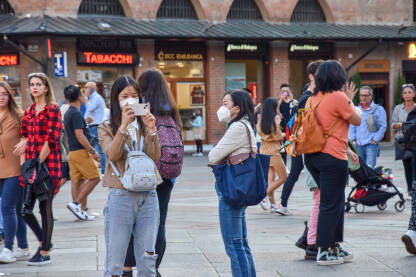 Grupa turista na ulici u Italiji. Ljudi šetaju i fotografišu ulice Bolonje. Žene na ulici.