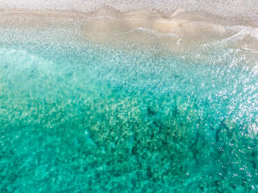Prekrasna tropska pješčana plaža tokom ljeta, snimci dronom. Morski valovi na pješačnoj obali. Prozirno tirkizno more.