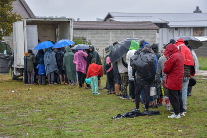Izbjeglice i migranti čekaju hranu koju im dijele lokalni volonteri u Velikoj Kladuši, Bosna i Hercegovina. Ljudi iz Afrike i Azije stoje u redu po kiši i čekaju hranu u improvizovanom kampu.