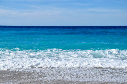 Talasi, morska pjena i čisto plavo more tokom sunčanog dana.