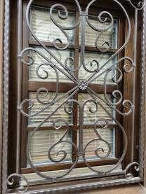 Metalna rešetka na prozoru. Rešetka od kovanog gvožđa postavljena na prozor zbog zaštite i estetike.