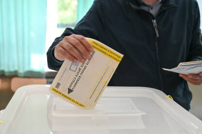 Čovjek stavlja glasački listić u kutiju. Birači na dan izbora. Ljudi izlaze na izbore. Predsjednički i parlamentarni izbori.