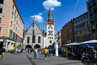 München, Njemačka: Ljudi šetaju glavnim trgom u centru grada. München, Njemačka: Ljudi šetaju glavnim trgom u centru grada. Marienplatz. Zgrade u historijskom dijelu grada. Altes Rathaus, Stara gradska vijećnica sa satom.