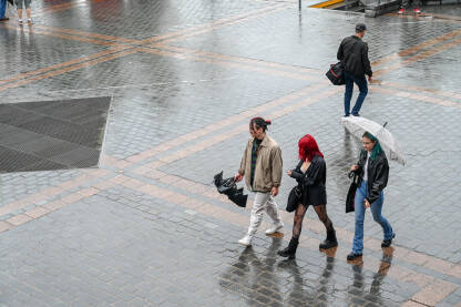 Mladi ljudi šetaju po kiši u gradu.